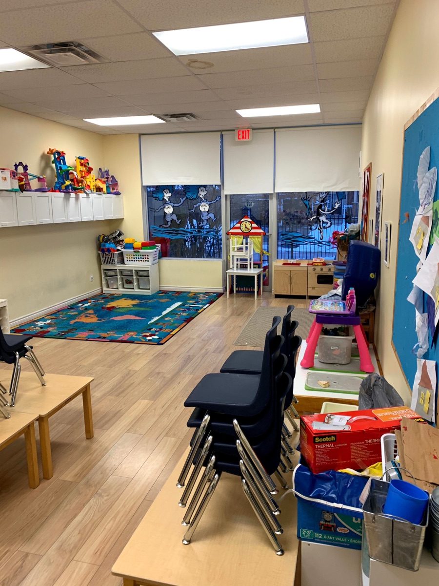 A preschool classroom with child-size tables, shelves, toys, and learning centers.